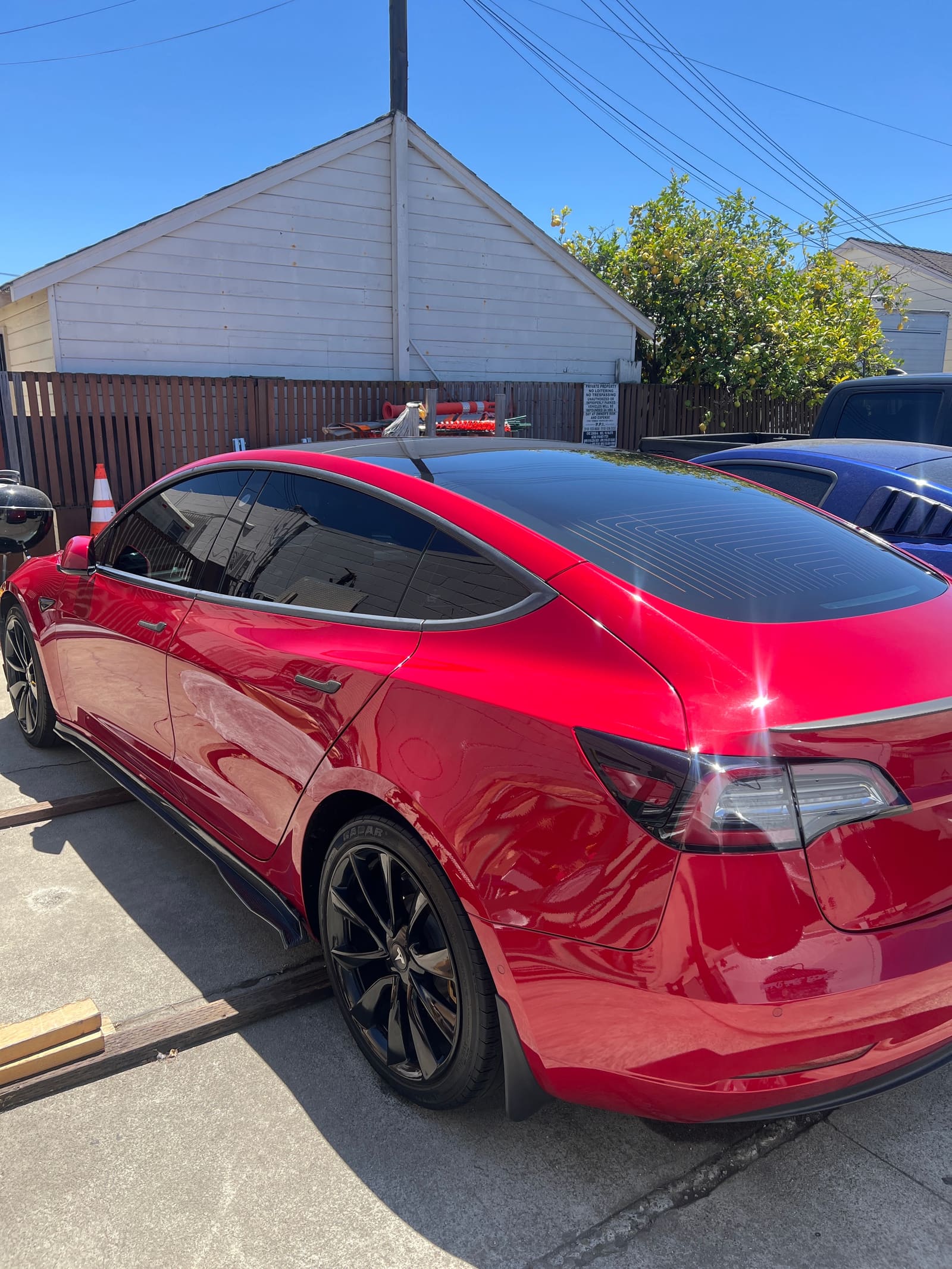 Red Tesla Model 3, rear three-quarter, paint gleaming after a detail